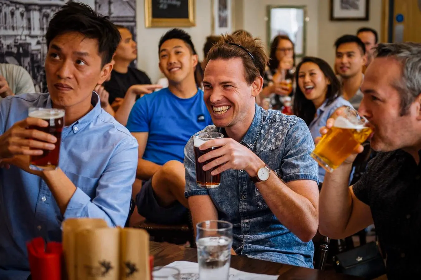 A group of friends drinking pints and watching live sport at The Flying Horse pub on Wilson Street, EC2A