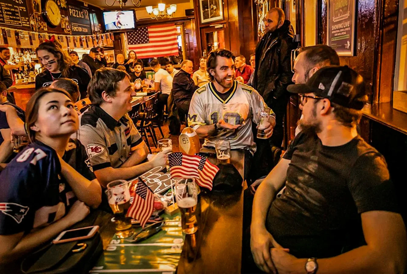 A packed crowd in sports jerseys watching a live event at The Flying Horse pub near Liverpool Street, EC2A