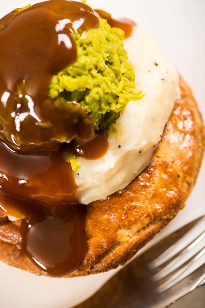 Close-up of a gourmet burger with mashed potato, guacamole, and gravy.