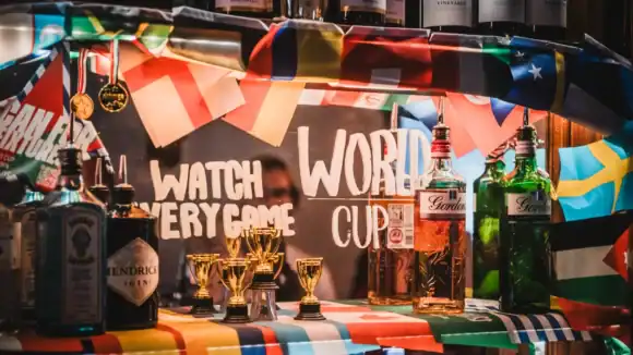 Bar setup with international flags, trophies, and alcohol bottles at The Flying Horse.