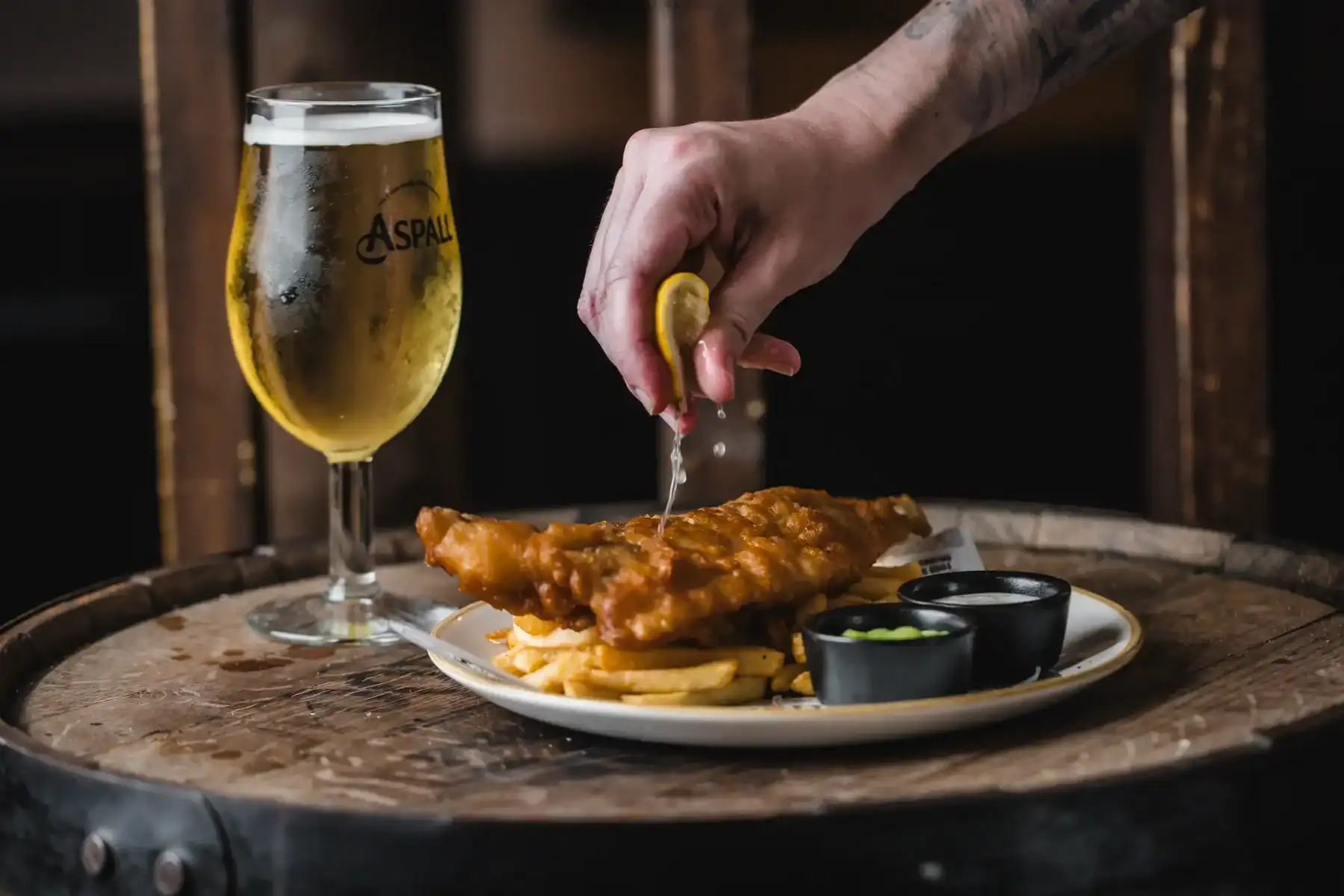 Serving fresh fish and chips with a lemon wedge and beer at The Flying Horse pub.