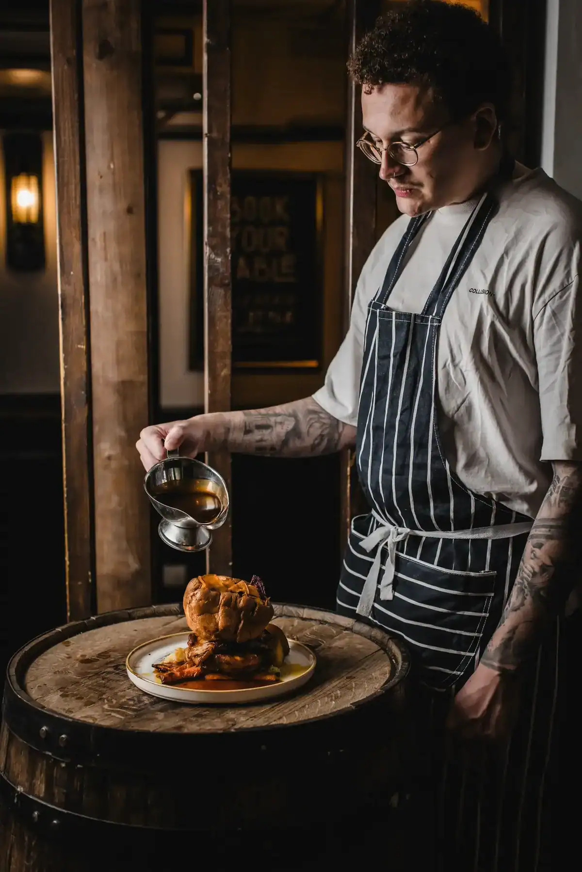 Chef pouring gravy over a roast chicken at The Flying Horse pub.